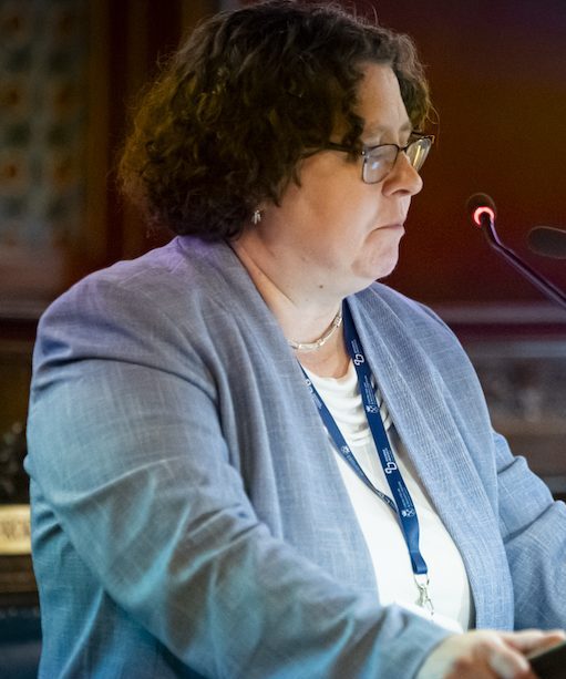 Elizabeth Clark speaking from the podium in Krakow, Poland.